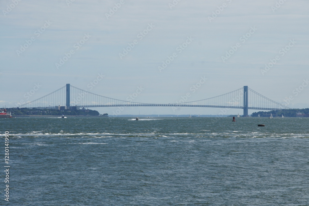 New York, Manhattan's iconic skyline stretches across the East River, dwarfed by the majestic Verrazano-Narrows Bridge in the distance. This suspension bridge connects Staten Island to Brooklyn, a New York, Manhattan's iconic skyline stretches across the East River, dwarfed by the majestic Verrazano-Narrows Bridge in the distance. This suspension bridge connects Staten Island to Brooklyn, a