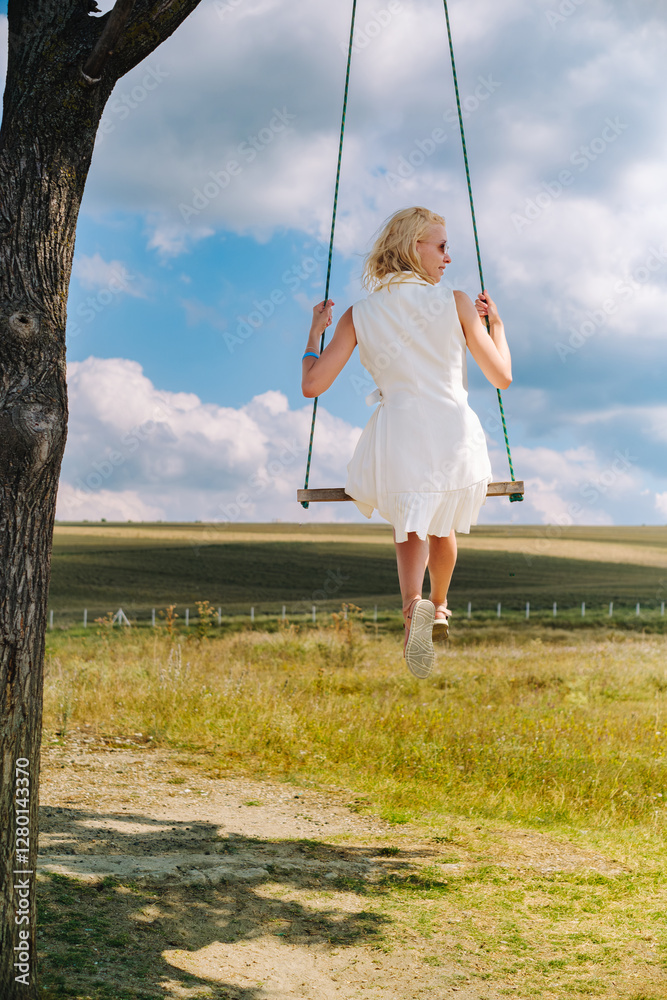 A girl is swinging on a swing under a tree on a sunny day. A girl is swinging on a swing under a tree on a sunny day.