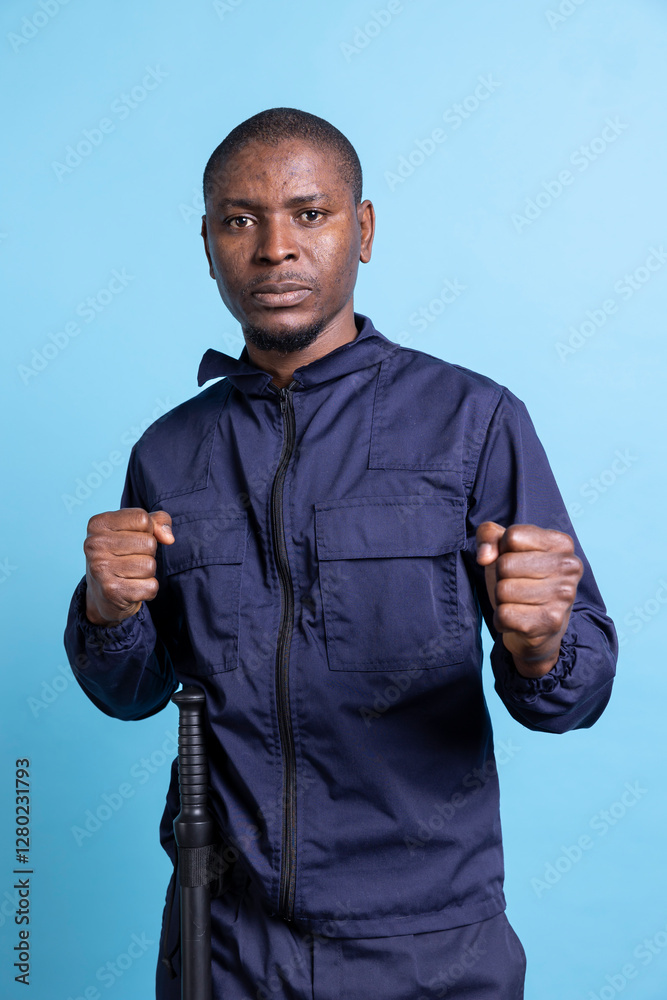 Fototapeta premium Confident security officer with fighting skills and experience posing in studio, standing with clenched fists ready to throw punches on duty. Guard protecting the premises, necessary safety measures.