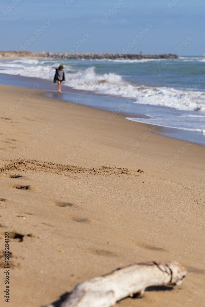 A peaceful day at the beach. Distant figure walking the shoreline, the ocean waves, soft sand. Perfect for contemplation and nature. A peaceful day at the beach. Distant figure walking the shoreline, the ocean waves, soft sand. Perfect for contemplation and nature.