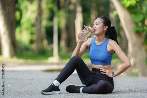 Quadro su tela Happy sporty woman enjoying fresh water from a bottle while sitting and resting