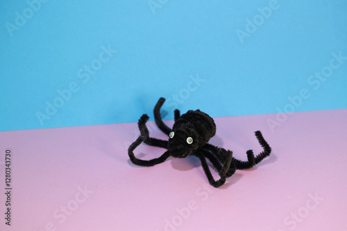 DIY Pipe Cleaner/DIY from Chenille Wire. A spider made from a pipe cleaner on a pink and blue background. Children's imagination. An idea for what to make with children in rainy weather.