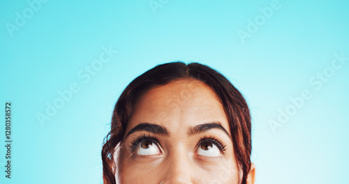 Closeup, eyes and woman in studio, thinking and problem solving on blue background. Person, looking up and model with ideas, thoughtful and solution with decision, option and choice with mockup space