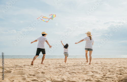 Canvas Print Asian family is flying a kite high in the sky while running on the beach