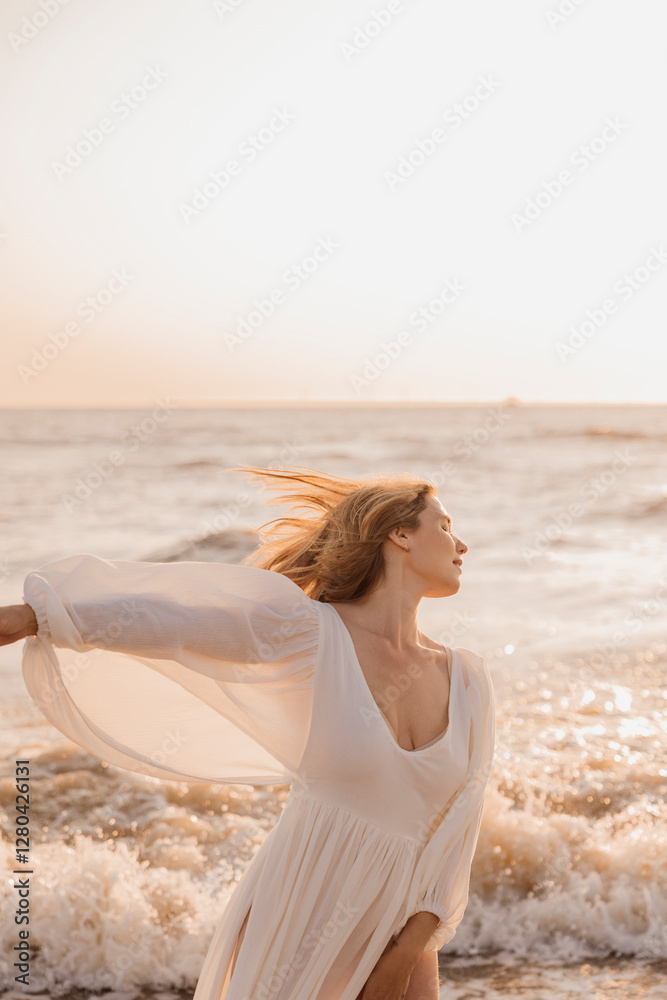 Woman in a flowing white dress standing in ocean waves at sunset Woman in a flowing white dress standing in ocean waves at sunset