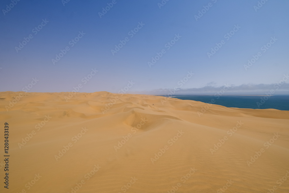 Endless golden dunes stretch towards the horizon, where the vast Namib Desert meets the Atlantic Ocean in the breathtaking wilderness of Sandwich Harbour, Namibia. Endless golden dunes stretch towards the horizon, where the vast Namib Desert meets the Atlantic Ocean in the breathtaking wilderness of Sandwich Harbour, Namibia.