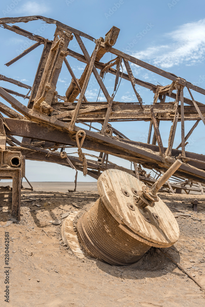wire reel and derrick of Drill Rig relic on desert sand, Old oil Rig site, Skeleton coast, Namibia