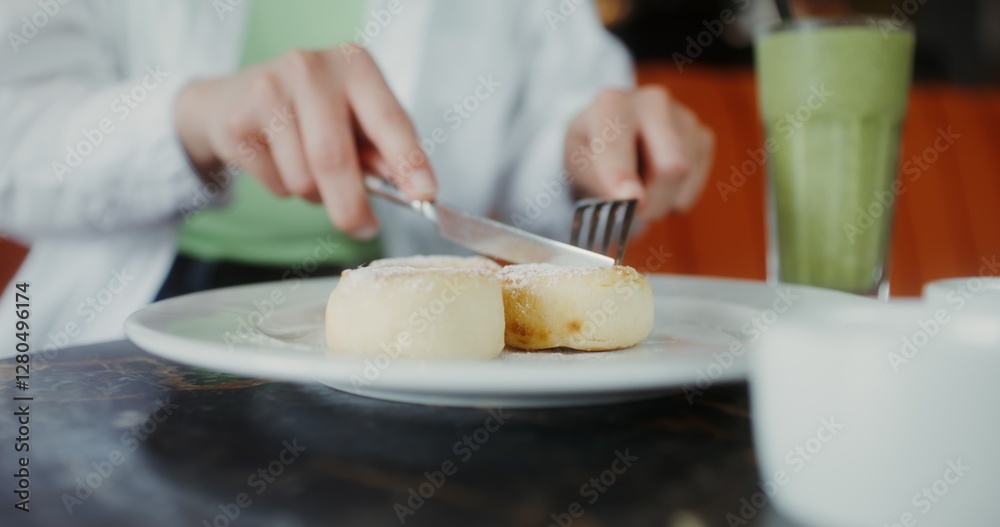 A woman eats cheesecakes, cutting them with a knife, close-up of female hands, no face A woman eats cheesecakes, cutting them with a knife, close-up of female hands, no face