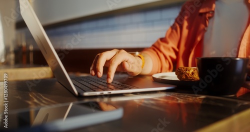 A man uses a laptop while sitting at a table in a cafe, close-up of a man's hands, no face