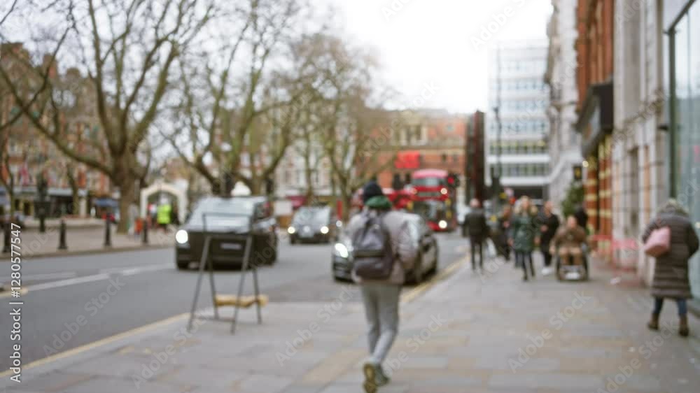 Blurred image capturing street of london with people, cars, and red bus in winter creating a dynamic city scene.