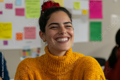 Smiling woman in cozy yellow sweater, expressing joy in creative workspace. Colorful sticky notes in background enhance vibrant atmosphere