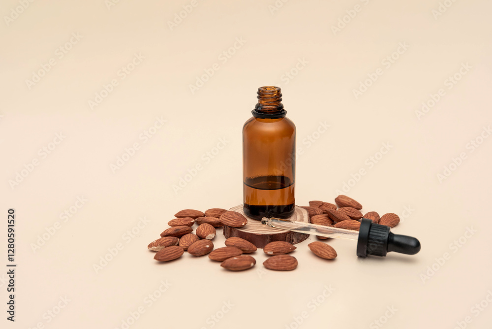 Almond essential oil in brown bottle with dropper on wooden slice with almonds around on beige background Almond essential oil in brown bottle with dropper on wooden slice with almonds around on beige background