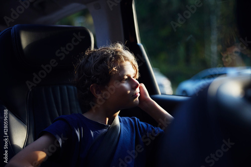 Wallpaper Mural Contemplative boy sitting in car while looking through window on road trip Torontodigital.ca