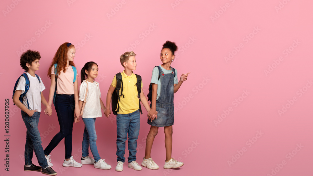 Obraz premium Body size portrait of schoolkids walking to school hand in hand on pink background
