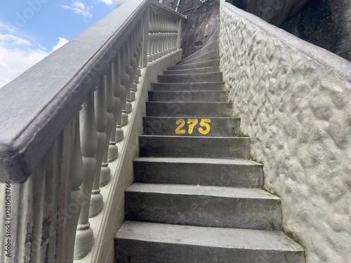 Stone staircase with number 275, leading upward against a textured wall.