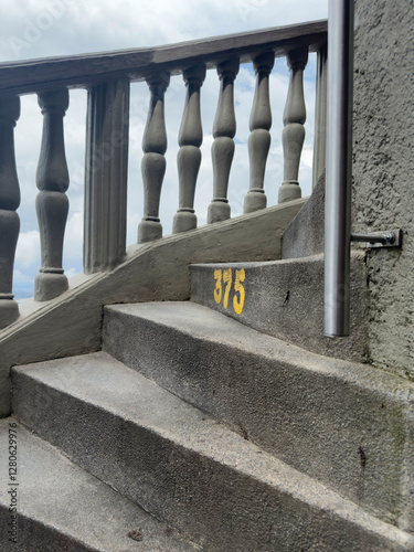 Concrete staircase with number 575 painted, gray balustrade visible on the side.