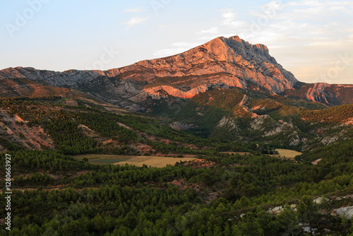 Sunset over Montagne Sainte-Victoire, near Aix-en-Provence, France. The warm evening light highlights the rugged limestone peaks, creating a stunning Provençal landscape.