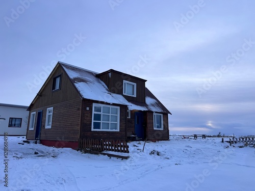 Traditional rorbu house in Keflavik, Iceland. Winter landscape with snowy mountains and Scandinavian cottage. photo