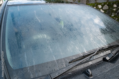A car window covered in mist, with condensation forming a foggy pattern, set in an outdoor environment