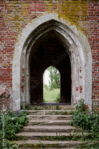 Entrance arch to an ancient abandoned Lutheran church near old Teutonic castle Brandenburg, with moss covered old red brickwork evoking timeless mystique