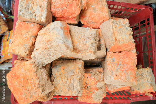 Fresh raw oncom displayed at a traditional food stall (warung), showcasing its textured surface and vibrant orange hue. A fermented soybean product used in Indonesian cuisine
