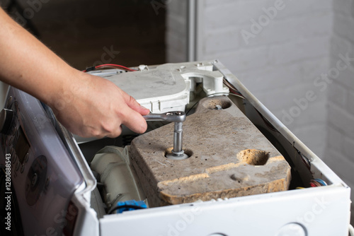 A washing machine repairman tightens the counterweight in the washing machine due to noise and vibration. Copy space for text photo