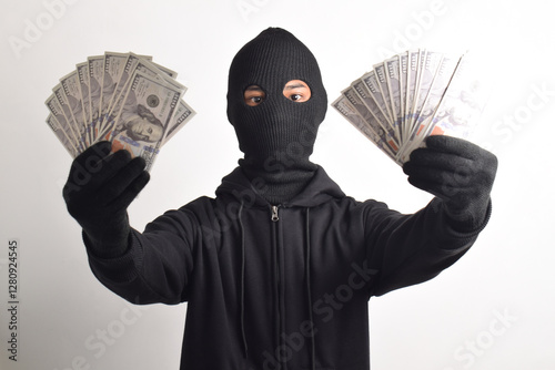 Thief wearing black jacket and mask showing dollar bills isolated on white background. Robbery and crime concept
