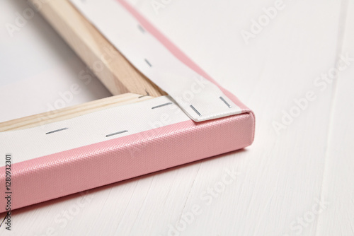 Close-up of the backside of a pink photo canvas print, showing neatly folded corners, tight stretching, and secure staples on a wooden frame against a white surface