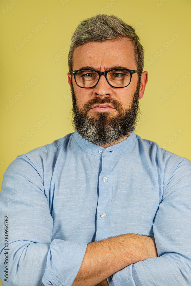 Obraz premium Man with gray beard and glasses stands confidently against yellow background