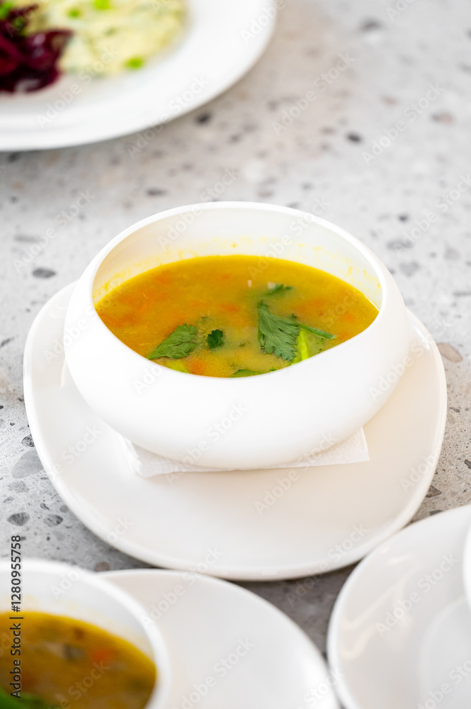 A steaming bowl of vibrant soup garnished with fresh herbs, placed elegantly on a minimalist stone table. Perfect for food styling, culinary themes, or healthy eating concepts A steaming bowl of vibrant soup garnished with fresh herbs, placed elegantly on a minimalist stone table. Perfect for food styling, culinary themes, or healthy eating concepts