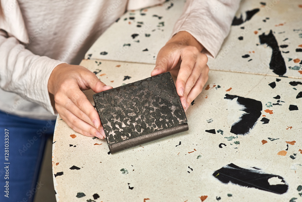 Hands holding elegant wallet on terrazzo table with modern design pattern, fashion accessory concept