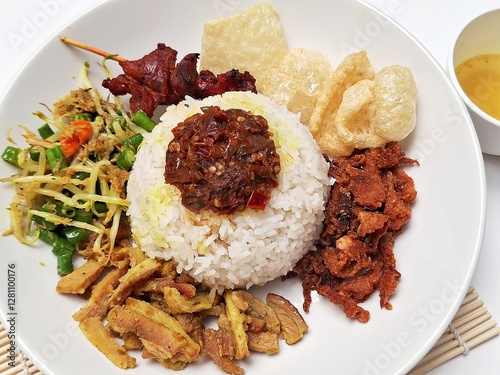 Bigul, or Nasi Campur Babi Guling, is a classic Balinese dish consisting of rice, roast pork, Balinese satay, and a selection of traditional side dishes from Bali, Indonesia. photo