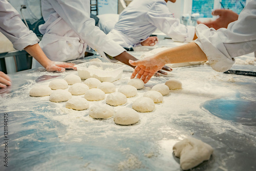 Hands of baking students working with fresh dough in a professional kitchen. Artisan bread preparation, teamwork, and pastry training in a culinary school. Flour, dough balls, and rolling techniques.