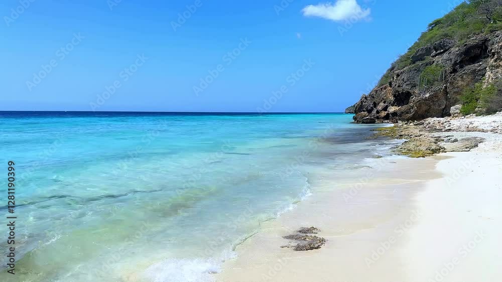 Clear blue water of Caribbean sea in Curacao island, small Dutch Antilles. White sandy beach with gentle waves lapping at the shore. The tropical atmosphere is peaceful and relaxing Clear blue water of Caribbean sea in Curacao island, small Dutch Antilles. White sandy beach with gentle waves lapping at the shore. The tropical atmosphere is peaceful and relaxing