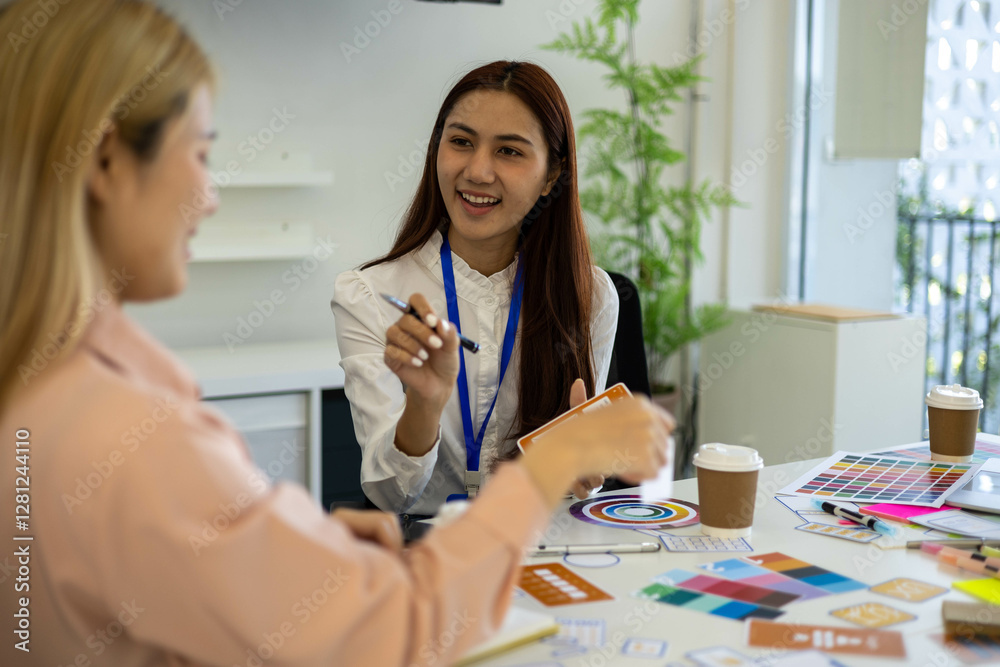 Obraz premium Two women are talking in a conference room. One of them is holding a piece of paper. The room has a whiteboard and a TV 