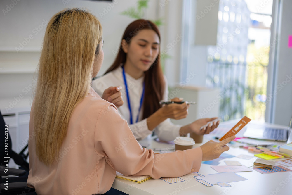 Two women are talking in a conference room. One of them is holding a piece of paper. The room has a whiteboard and a TV
Two women are talking in a conference room. One of them is holding a piece of paper. The room has a whiteboard and a TV