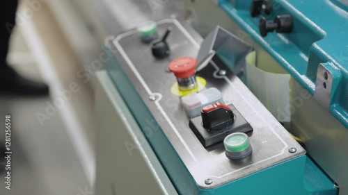 Close-up of man pushing buttons on sawing machine in workshop