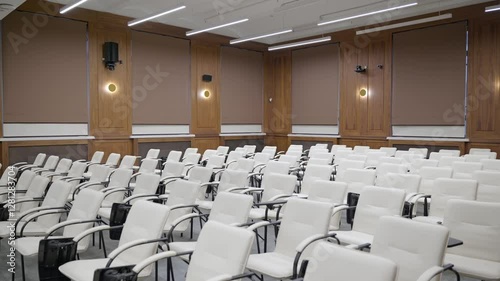 Modern empty classroom, lecture hall, with white chairs and brown wooden walls