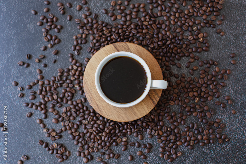 Naklejka premium Espresso coffee served in white cup with wooden saucer on dark moody background with roasted coffee beans scattered