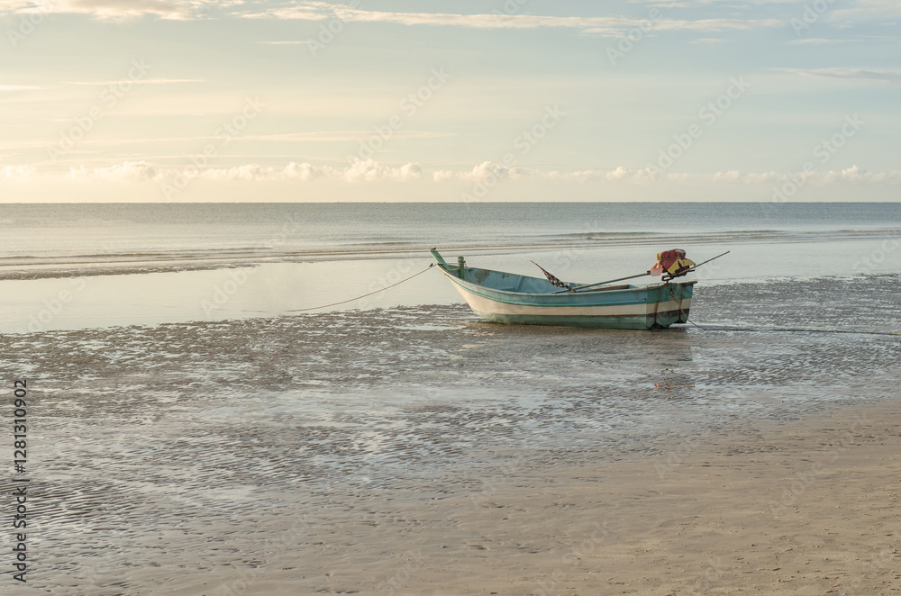 Lone boat on a tranquil, shallow beach at sunset Lone boat on a tranquil, shallow beach at sunset