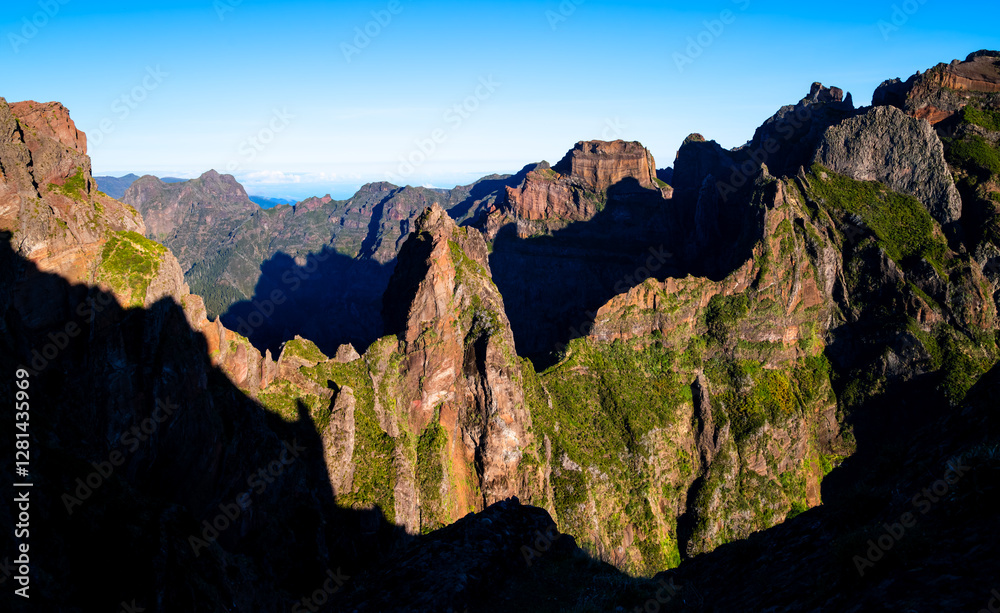 Obraz premium Wide angle landscape panorama on the famous hiking trail from Pico Areeiro to Pico Ruivo in warm morning sunlight. Impressive volcanic mountain range on the Atlantic island of Madeira (Portugal)