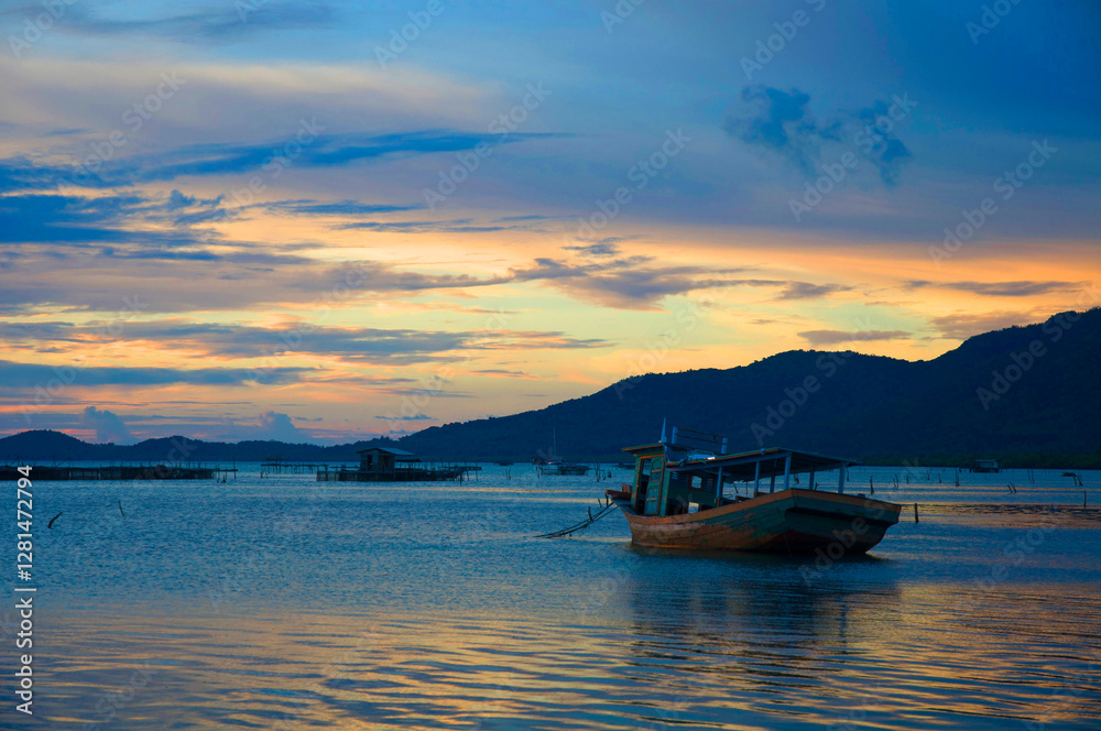 Water surface. View of a Sunset sky background. Dramatic gold sunset sky with evening sky clouds over the sea with a boat in silhouette. Water surface. View of a Sunset sky background. Dramatic gold sunset sky with evening sky clouds over the sea with a boat in silhouette.