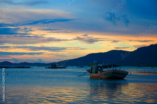 Water surface. View of a Sunset sky background. Dramatic gold sunset sky with evening sky clouds over the sea with a boat in silhouette.