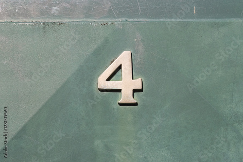 The metal number 4 on a green façade.