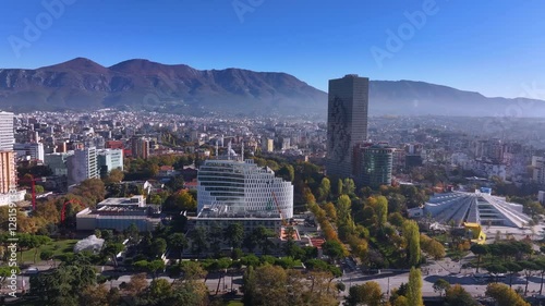 An aerial view of Tirana showcases the city's vibrant landscape, with Mount Dajt towering on the horizon. The mix of modern architecture, green spaces, and bustling streets creates a dynamic urban. photo