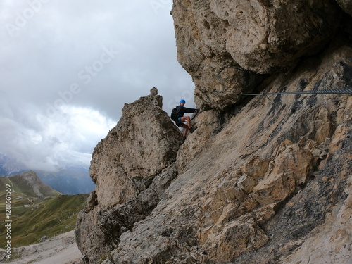 Uma figura solitária sobe uma montanha rochosa e acidentada, ofuscada pela paisagem imponente, incorporando o espírito da aventura humana e a busca por alturas. photo