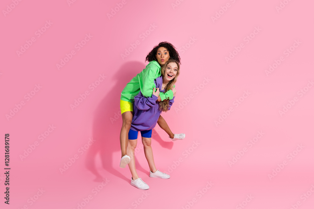 Cheerful young women having fun together in colorful casual outfits and pink backdrop Cheerful young women having fun together in colorful casual outfits and pink backdrop