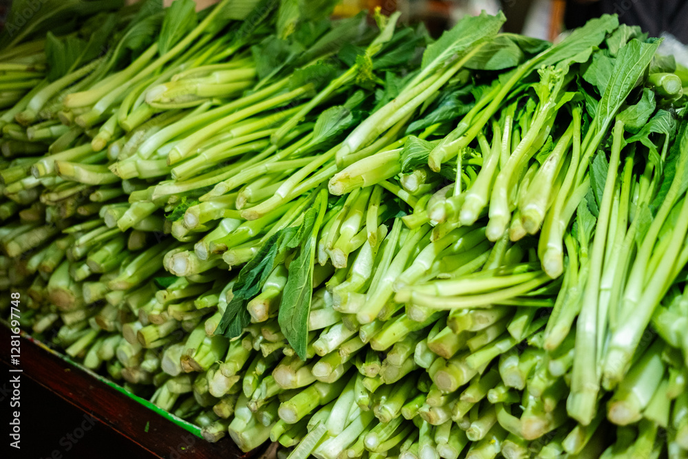 A large quantity of fresh raw mustard greens (sawi) displayed, showcasing their crisp texture and vibrant green leaves, commonly used in Asian cuisine A large quantity of fresh raw mustard greens (sawi) displayed, showcasing their crisp texture and vibrant green leaves, commonly used in Asian cuisine