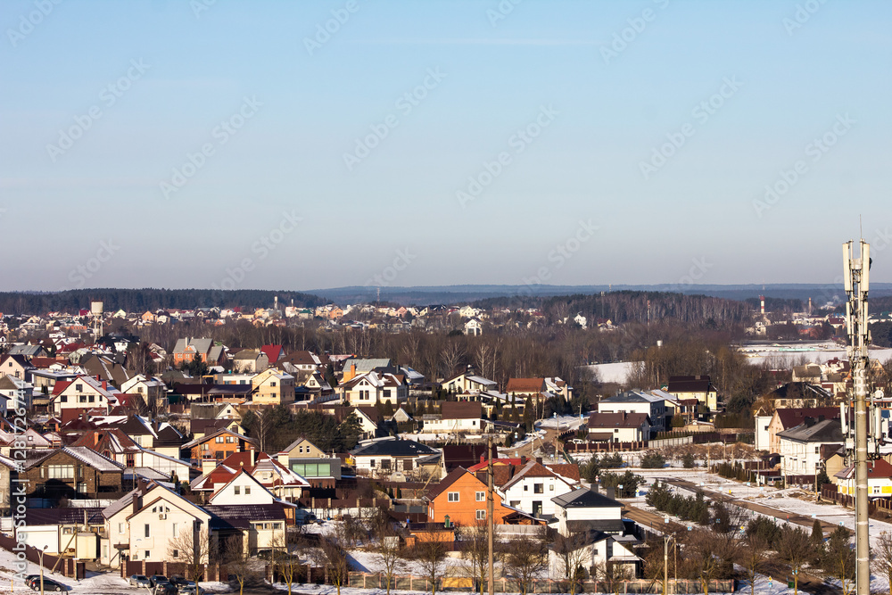 Obraz premium winter photography of a snowy suburban neighborhood, showcasing snow-covered houses and trees in a peaceful setting, perfect for seasonal marketing and landscape visuals.