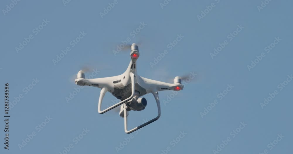 Drone is flying high in sky. Radio-controlled Quadcopter in flight against blue sky. Drone Quadcopter Hovers in slow motion. Flight quadcopter in sky. UAV Drone is flying high in sky. Radio-controlled Quadcopter in flight against blue sky. Drone Quadcopter Hovers in slow motion. Flight quadcopter in sky. UAV
